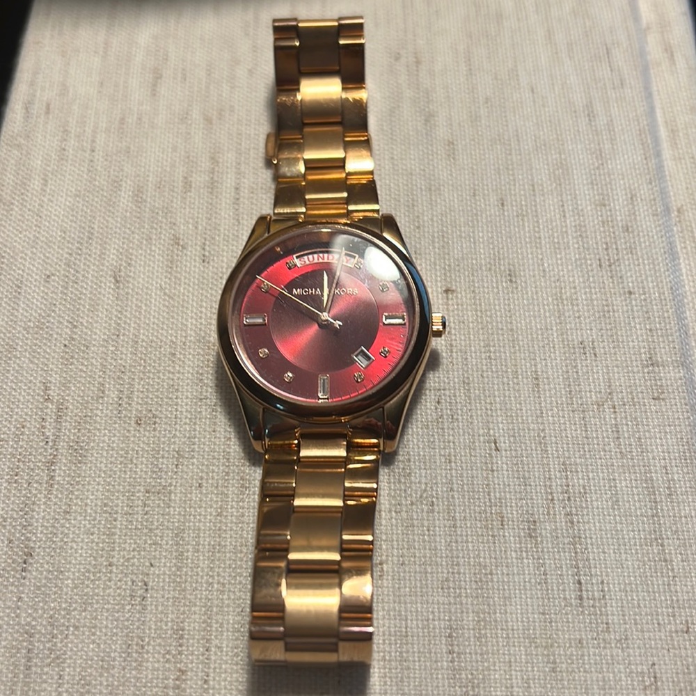 Gold Michael Kors stainless steel watch with red face and rhinestone numbers